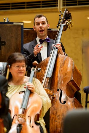 Closeup shot of CSO principal bass Alexander Hanna smiling and pointing to the camera in an inviting way