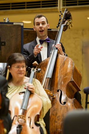 Closeup shot of CSO principal bass Alexander Hanna smiling and pointing to the camera in an inviting way
