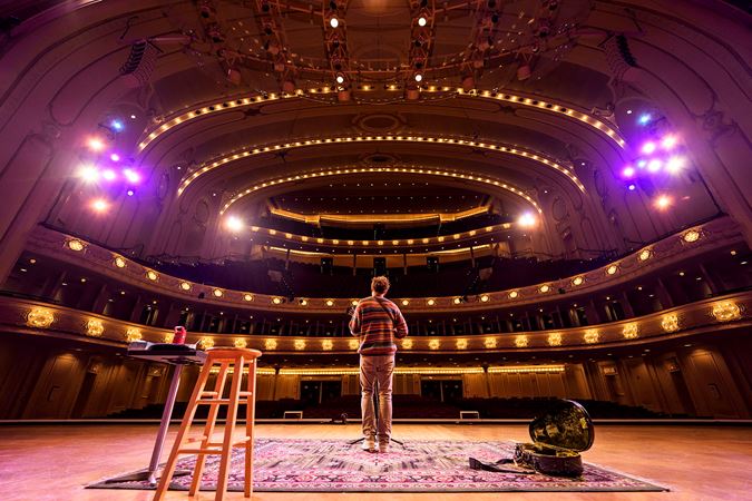 a view from the stage behind Chris Thile as he rehearses for his Symphony Center show