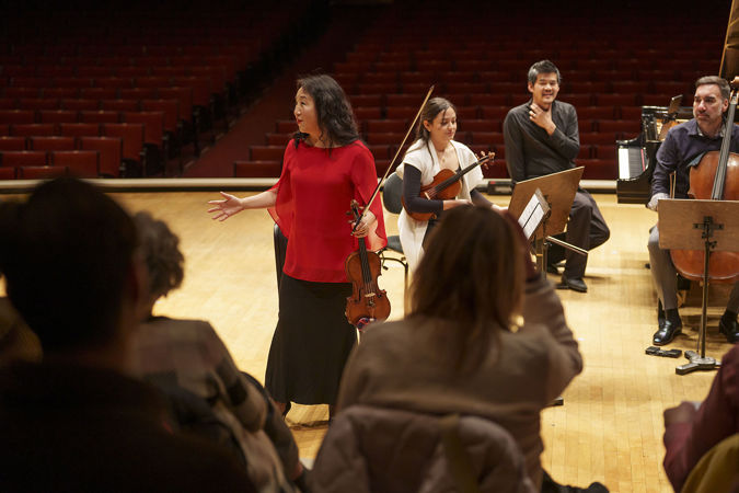 Closeup of CSO violin Yuan-Qing Yu speaking with the audience on stage