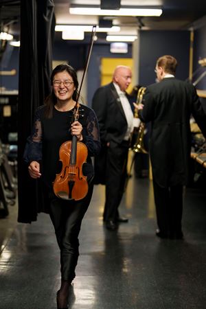 A CSO musician smiling backstage about to walk on stage to warm up