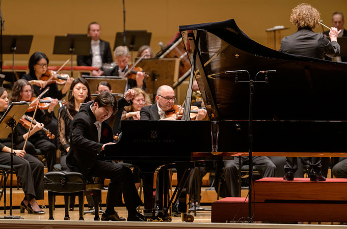 Seong-Jin Cho playing the piano on stage with the Chicago Symphony Orchestra