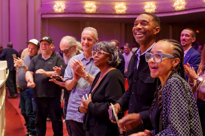 the front row of audience members gives an enthusiastic standing ovation