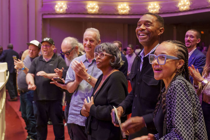 the front row of audience members gives an enthusiastic standing ovation