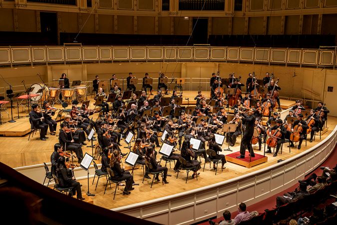 Wide shot of principal conductor Ken-David Masur leading the Civic Orchestra of Chicago on stage