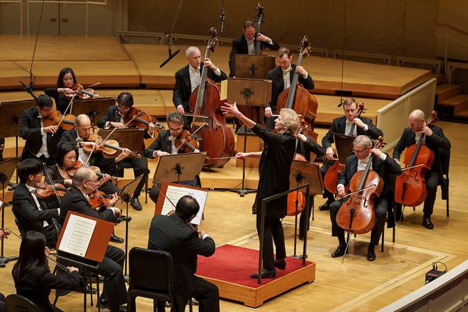 Dame Jane Glover gestures animatedly on the podium