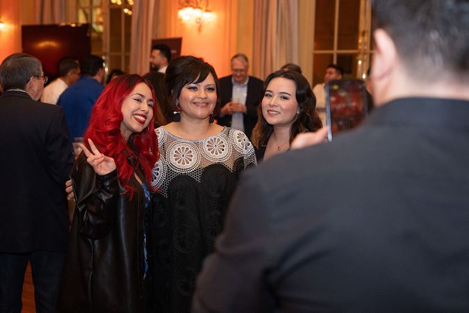 two Latino Alliance members pose for a photo with Tres Souls member Rocio Mendoza at the postconcert reception