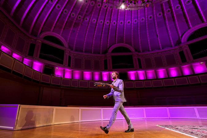 Chris Thile walks off stage after his final bow, mandolin swinging in his left hand
