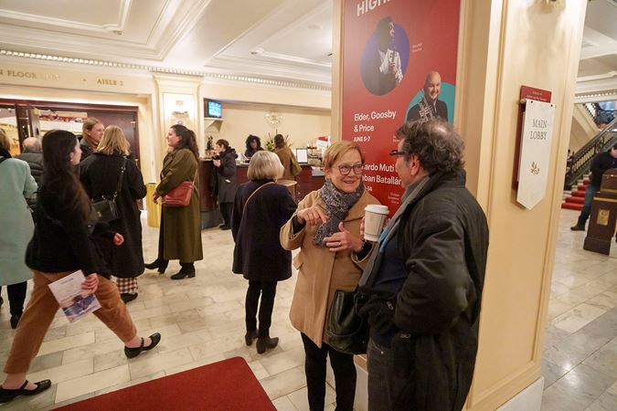 audience members mingle and drink coffee in the lobby before the concert