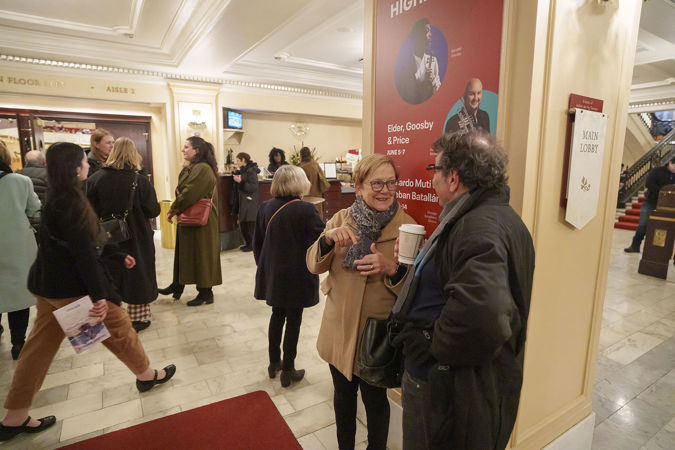 audience members mingle and drink coffee in the lobby before the concert