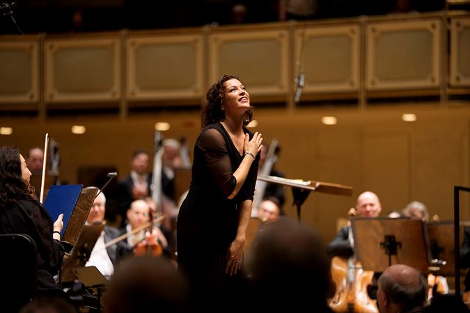 wearing a flowy black pantsuit, Ksenija Sidorova smiles and takes a bow after her solo encore