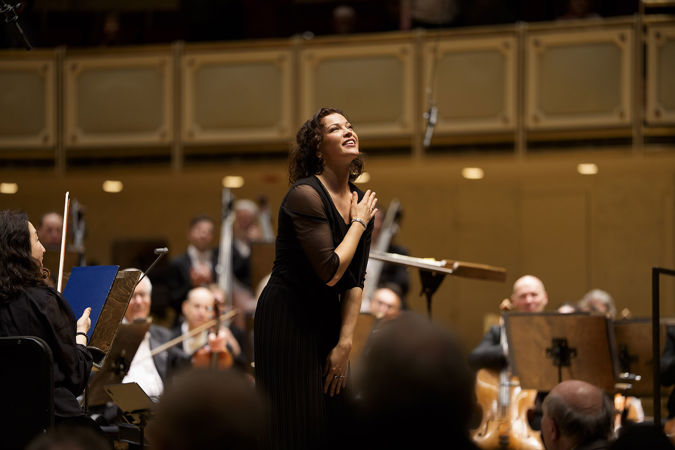 wearing a flowy black pantsuit, Ksenija Sidorova smiles and takes a bow after her solo encore