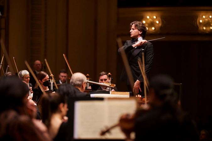 conductor Gustavo Gimeno gestures to the Orchestra with baton in hand
