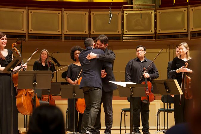 Composer-Curator Jimmy López hugs his collaborator and friend, conductor Nicholas Koo