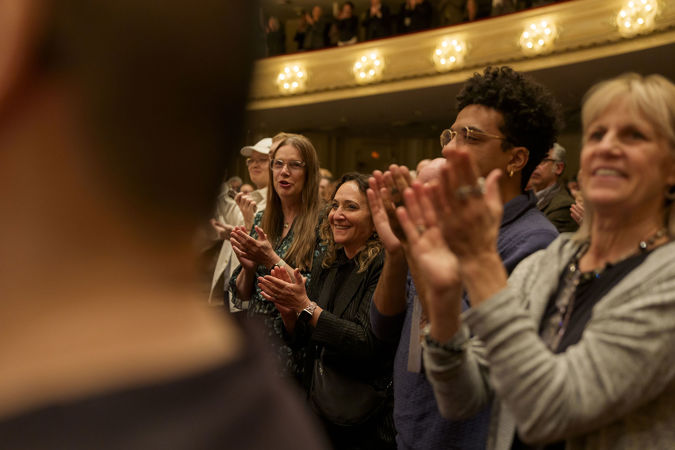 Closeup shot of audience members applauding violinist Augustin Hadelich, guest conductor Philippe Jordan and the CSO