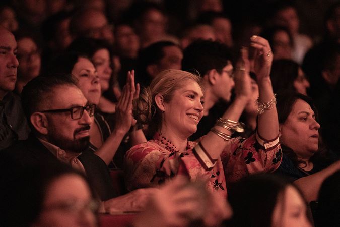 audience members on the main floor smile and clap enthusiastically for Tres Souls' performance