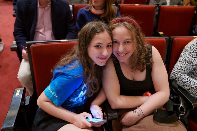 Two audience members smiling at the camera as they wait for the concert to begin