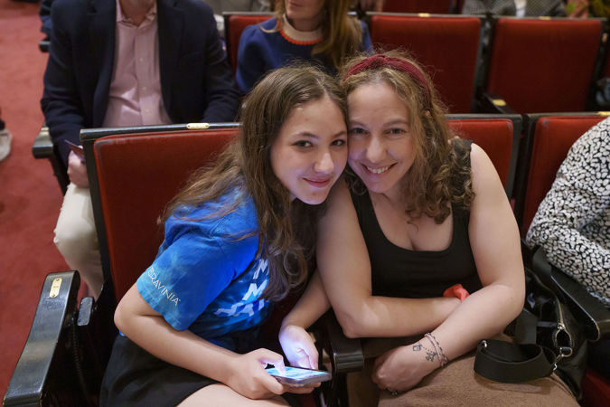 Two audience members smiling at the camera as they wait for the concert to begin