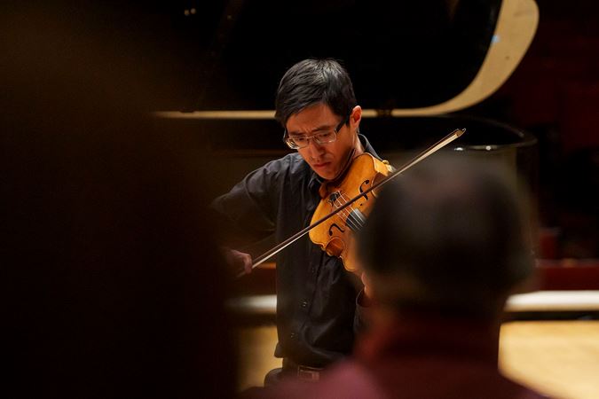 Closeup of CSO viola Danny Lai performing on stage