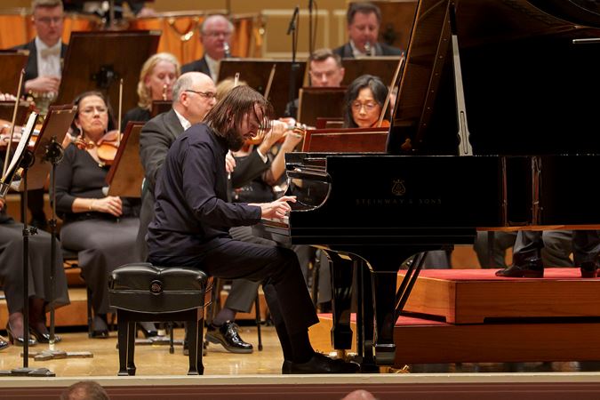 Daniil Trifonov's fingers fly across the keyboard, hair flying as he performs a particularly difficult passage of Brahms' Second Piano Concerto