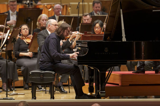 Daniil Trifonov's fingers fly across the keyboard, hair flying as he performs a particularly difficult passage of Brahms' Second Piano Concerto