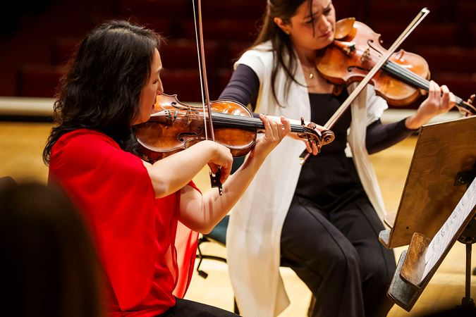 Closeup of CSO violin Yuan-Qing Yu playing on stage