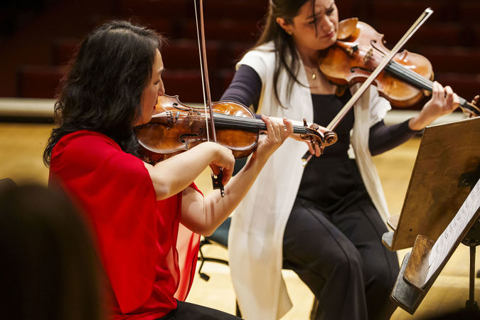 Closeup of CSO violin Yuan-Qing Yu playing on stage