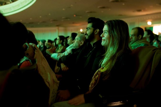 audience members smile during the concert, bathed in a green glow from the stage lights