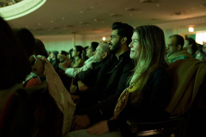 audience members smile during the concert, bathed in a green glow from the stage lights