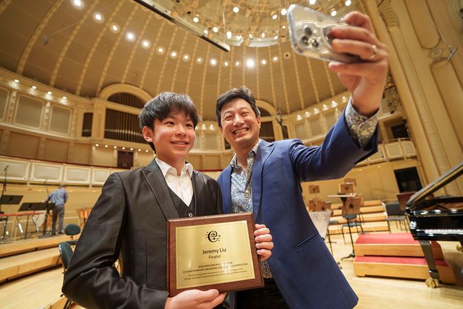 2025 Young Artists Competition winner Jeremy Liu holding is award and taking a selfie with a family member