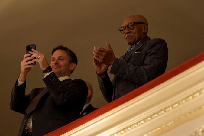 audience members in the balcony take photos of the Orchestra's final bows