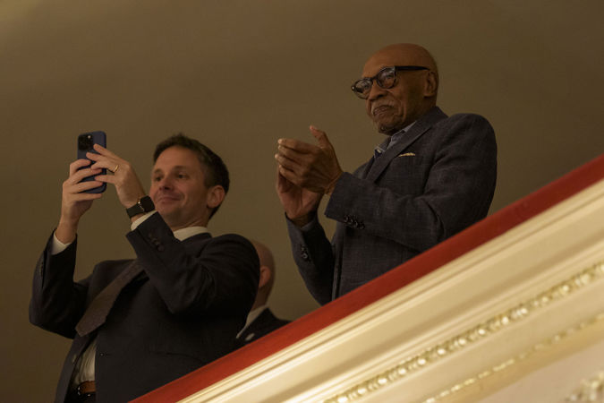 audience members in the balcony take photos of the Orchestra's final bows