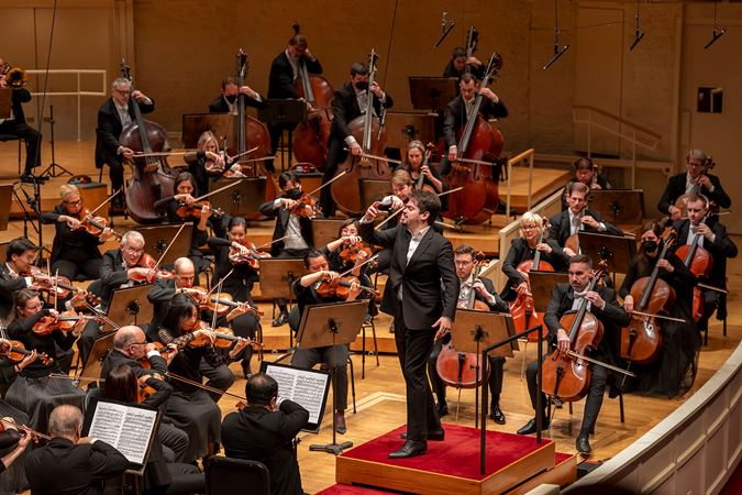 Shani conducts the orchestra in Brahms' First Symphony