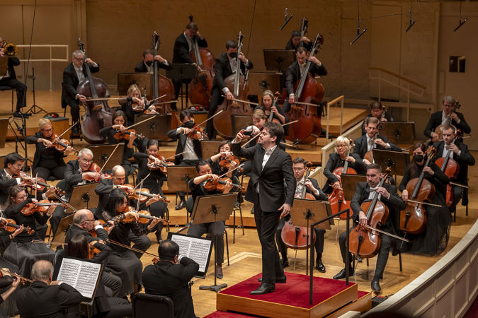 Shani conducts the orchestra in Brahms' First Symphony
