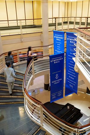 Symphony Ball signs hanging in the rotunda and patrons walking up the stairs