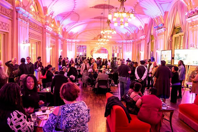 guests mingle in a packed Grainger Ballroom, complete with purple mood lighting, couches and chandeliers