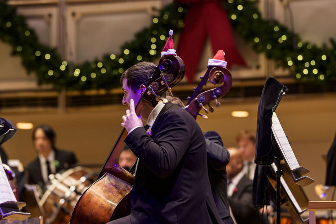 Closeup of CSO basses on stage with santa hats on their basses
