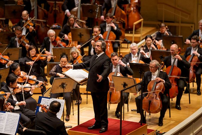 Muti leads the Orchestra from the podium, baton in hand as he pivots toward the violin section