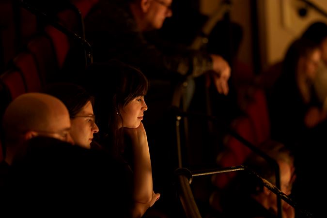 audience members watch intently from the upper balcony