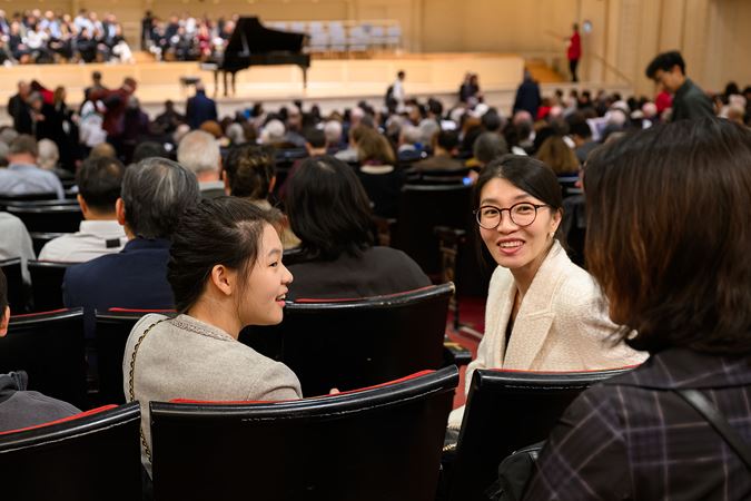 audience members on the main floor have an animated conversation as the hall fills up for the concert