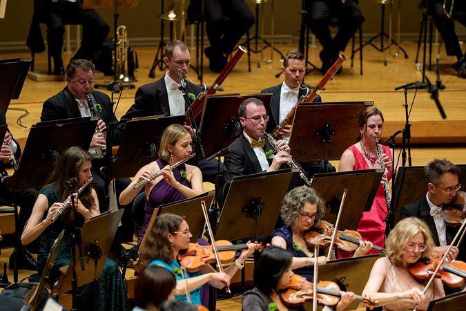 Group shot of the CSO clarinet, bassoon, flute, oboe and violin section performing on stage