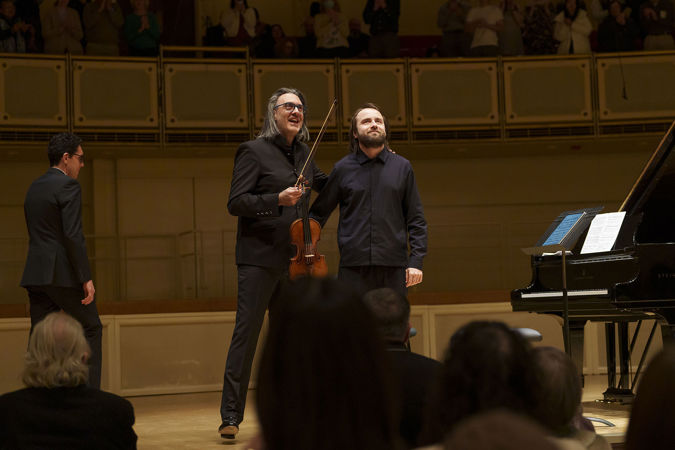 Leonidas Kavakos & Daniil Trifonov smiling on stage in front of an applauding audience