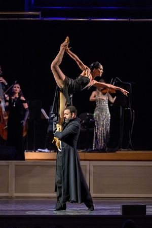 two dancers perform an impressive lift, with the woman stretching an arm and a leg up in the air for extra height