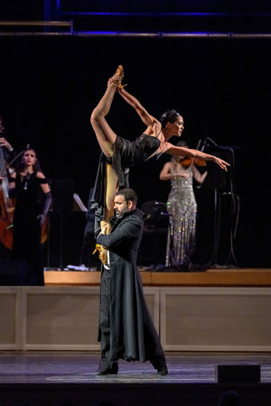 two dancers perform an impressive lift, with the woman stretching an arm and a leg up in the air for extra height
