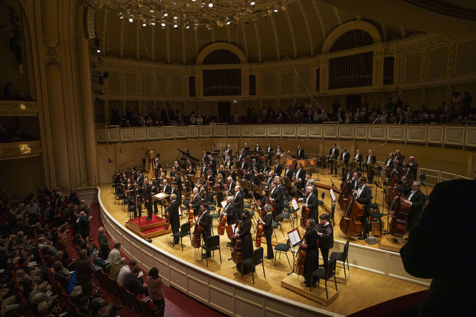 a point of view from the right side of the box level of the Orchestra and Karina Canellakis bowing together
