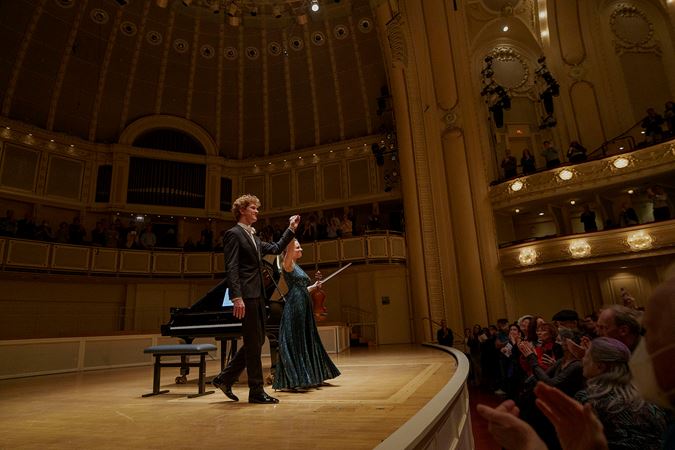violinist Julia Fischer and pianist Jan Lisiecki holding hands and bowing together
