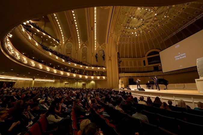 the audience looks on as TwoSet Violin performs a piece inspired by The Bean in Chicago