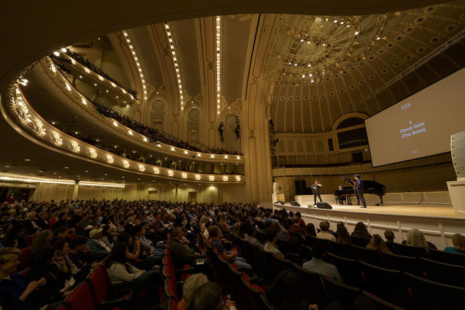 the audience looks on as TwoSet Violin performs a piece inspired by The Bean in Chicago