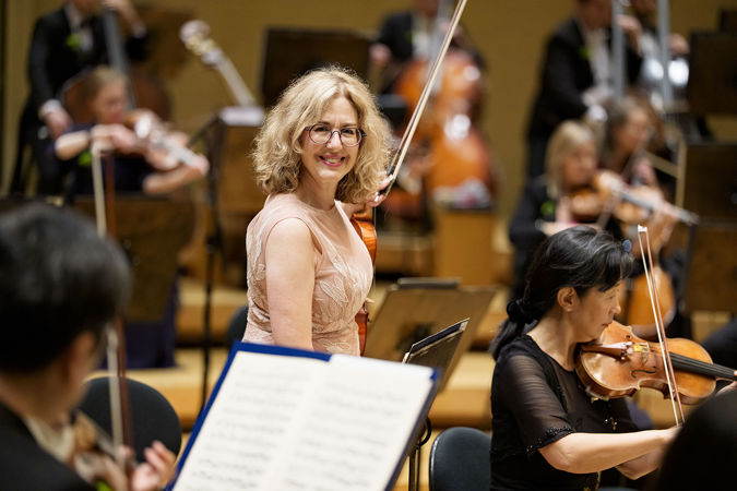Closeup shot of CSO violin Florence Schwartz smiling and going to her seat on stage before the concert