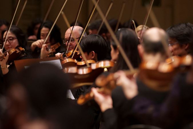 a sea of violins and violas with their bows pointing upwards at varying angles